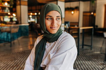 Thoughtful Muslim woman sitting in a cafe