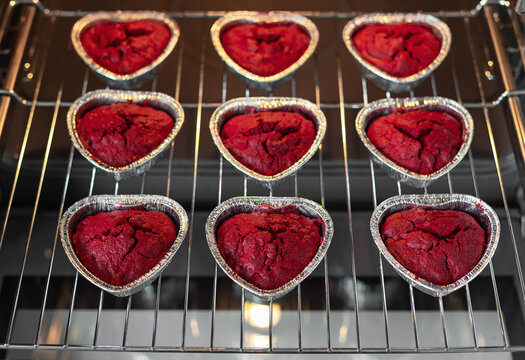 Delicious red velvet cupcakes baking in an oven. Heart shape cupcakes on baking tray. Valentines day concept. soft focus