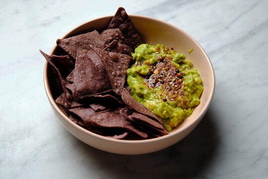 Chocolate taco chips with guacamole in a pink bowl