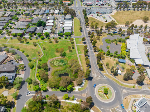 Aerial view of a large roundabout and road network through parkland and an outer city suburb