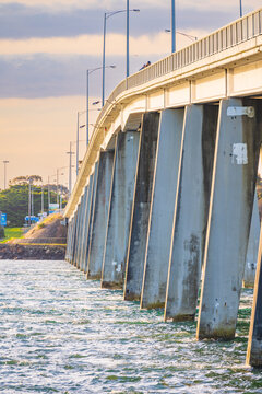 A row of concrete pylons supporting a long bridge over a coastal bay