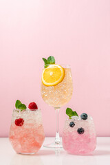 Set of drinks with ice in glasses. Raspberry, blueberry and orange cocktails. Refreshing tropical...