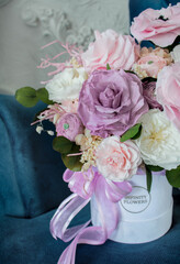 Cozy room, flowers in box on blue armchair. Preserved flowers bouquet closeup. Eternal, stabilized, forever rose flower.