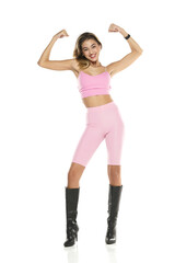 a young happy woman in pink short leggings and top, and black leather boots on a white background