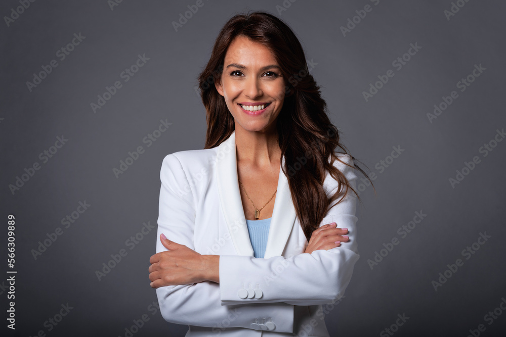 Wall mural Studio portrait of a brunette haired beautiful woman standing at isolated grey background