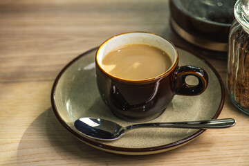 cup of hot Instant coffee dark shot in cup with crema on wooden table and beans . coffee beans and cup full of Intense dark shot coffee in glass cup