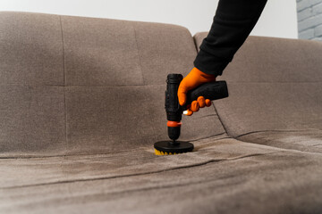 Close-up process of dry cleaning for removing stains and dirt from couch at home. Professional...
