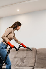 Cleaner girl is cleaning couch with extraction machine for dry clean upholstered furniture....