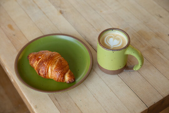 latte and croissant with green dishes