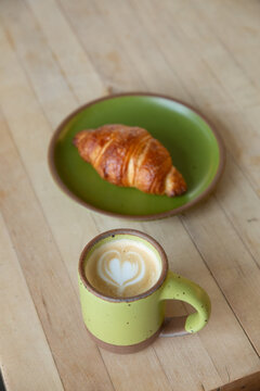 latte and croissant with green dishes