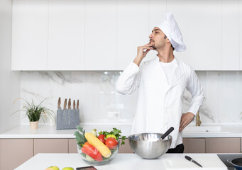 Young handsome male chef posing while cooking in the kitchen