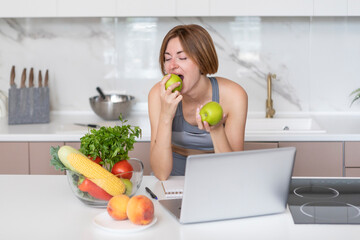 Young fit woman in sportswear sitting in the kitchen and thinking about her diet plan