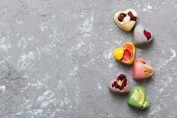 chocolate sweets in the form of a heart with fruits and nuts on a colored background. top view with space for text, holiday concept