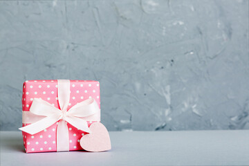 gift box with red bow and red heart on colored background. Perspective view. Flat lay