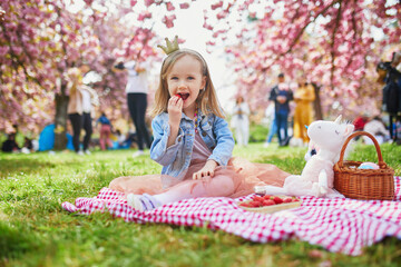 preschooler girl in tutu skirt enjoying nice spring day in cherry blossom garden - obrazy, fototapety, plakaty