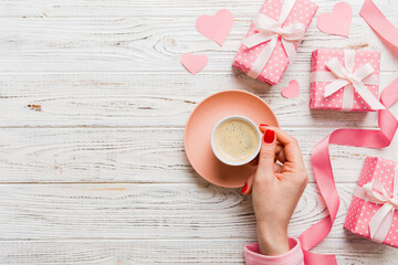 Flat lay of heart shaped cup of black coffee in the hands of women on colored background with copy space top view. Valentine day and holiday concept