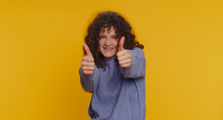 Like. Pretty curly haired woman in sweater raises thumbs up agrees with something or gives positive...