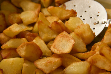 Closeup of some home fries with a metallic spatula to move them