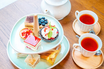 Top view of sweet delights with afternoon tea stand, teapot and tea cups