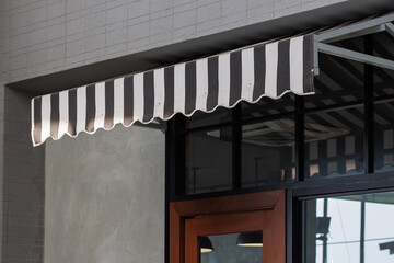 the black and white striped awning over the shop door. exterior canvas roof. blind sun