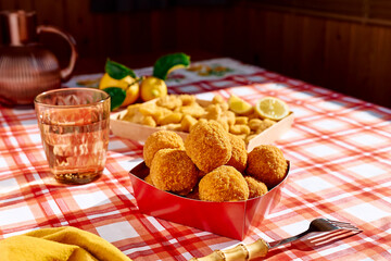 Typical Sicilian street food arancini (deep fried rice balls with meat) on paper plate take out. Unhealthy food.