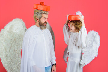 Valentines day. Little son and father in angel wings with gift on head. Valentine present.