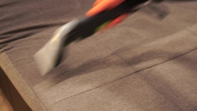 4k video housekeeper is extracting dirt from upholstered sofa using dry cleaning extractor machine. Cleaner girl is cleaning couch with extraction machine for dry clean upholstered furniture.