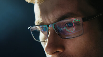 Portrait of trader wearing eyeglasses with reflection cryptocurrency chart. Close-up portrait of man analysing stock market. Copy space - obrazy, fototapety, plakaty