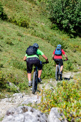 Fototapeta na wymiar Zwei Mountainbiker bei einer kniffligen Fahrt auf einem verblockten Single Trail im Gebirge