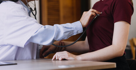 Homecare nursing service and elderly people cardiology healthcare. Close up of young hispanic female doctor nurse check mature caucasian man patient heartbeat using stethoscope during visit