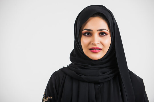 Beautiful woman from Dubai posing on colored background with traditional abaya.