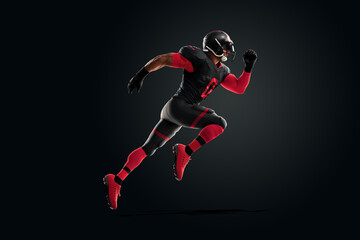 Fototapeta na wymiar American Football player in red and black uniform in running pose on black background. American Football, advertising poster, template, blank, sports. 3D illustration, 3D rendering.