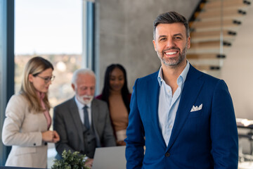 Happy smiling bearded businessman company leader or sales manager, successful entrepreneur standing in front of diverse coworkers team smiling and looking at camera.