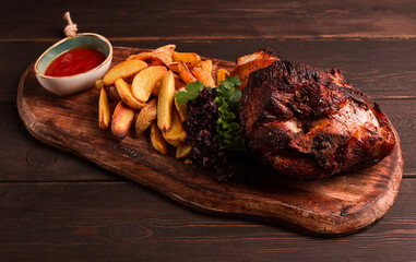 Pork knuckle, in soy-honey sauce, with fried potatoes, on a wooden chopping board, homemade, no people,