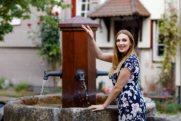 Beautiful young woman with long hairs in summer dress going for a walk in German city. Happy girl...