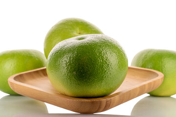 In the foreground, a single organic juicy Citrus Sweetie on a bamboo plate, close-up, against a white background. In the background are three Citrus Sweetie .