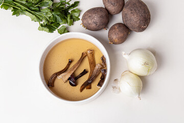 Soaking dried wild mushrooms. Dried mushrooms, potatoes, onions and parsley. Ingredients for making soup. Top view