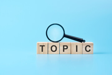 wooden blocks with the text: topic with magnifying glass. business concept