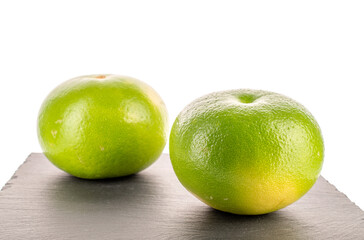 Two ripe Citrus Sweetie on a serving slate board, close-up, isolated on a white background.