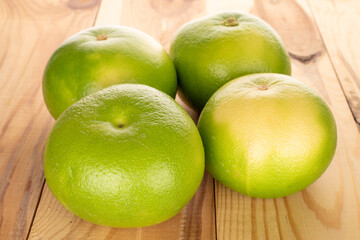 Several organic bright green Citrus Sweetie on a wooden table, close-up.