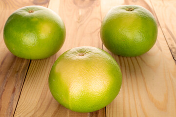 Three organic ripe Citrus Sweetie on a wooden table, close-up.