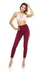 Fototapeta na wymiar a young woman in burgundy jeans and top, and high heels shoes posing on a white background