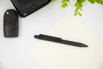 Businessman concept. flat lay black pen on white page next to black wallet and car keys.