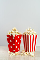 two bags of popcorn in red and white on a light background, front view, copy space