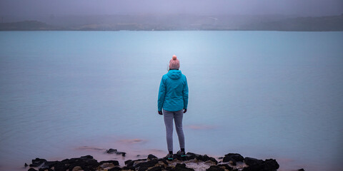 Girl in blue jacket looks at stunning blue colored lagoon near Gunnuhver Hot Springs. Hidden gems of Iceland  © Lens Down Under