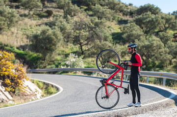 Obraz premium Cyclist stand up with his bicycle in front with only one wheel on the floor at the mountain