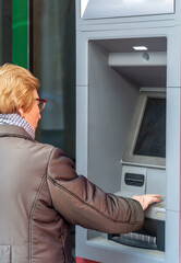 Fototapeta na wymiar An elderly woman uses an ATM