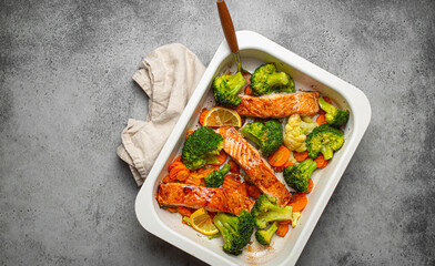 Top view of healthy baked fish salmon steaks, broccoli, cauliflower, carrot in casserole dish. Cooking a delicious low carb dinner, healthy nutrition concept