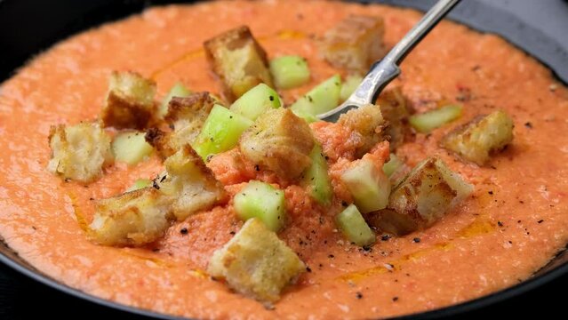 Eating Spanish Gazpacho soup with tomatoes, vegetables and croutons