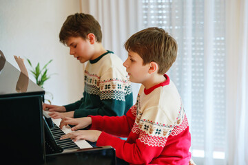 two preteen boys playing piano in living room. Children having fun with learning to play music...
